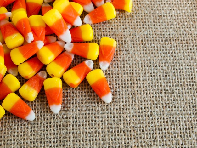 Traditional Halloween candies candy corn on burlap fabric.