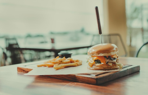 Photo traditional hamburger with fries served on a restaurant table appetizing burger with fries served on a wooden table