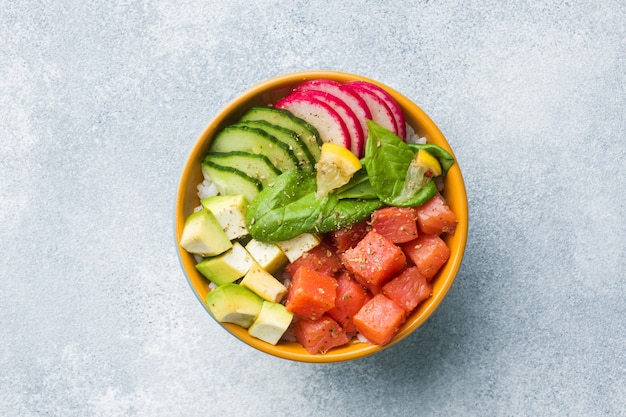 Photo traditional hawaiian poke salad with salmon, avocado rice and vegetables in a bowl.