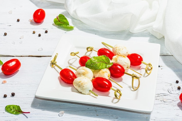 Фото Традиционное здоровое итальянское закуска моцарелла свежие листья и вишневые помидоры на шипах