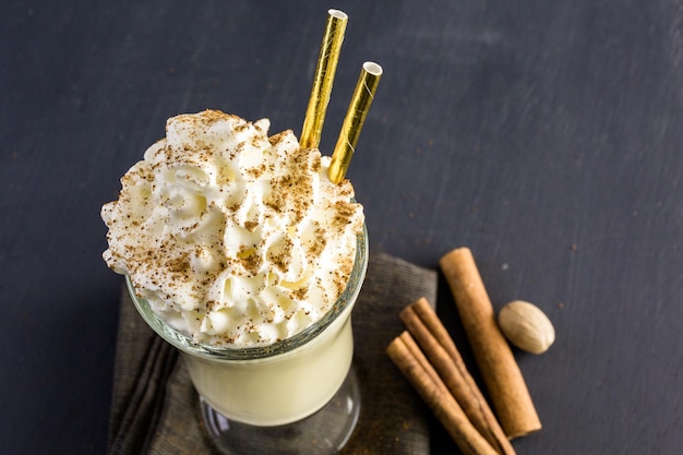 Traditional holiday drink egg nog garnished with whipped cream in the glass.