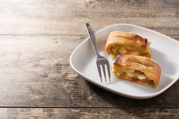 Photo traditional homemade apple strudel slice on wooden table, copy space