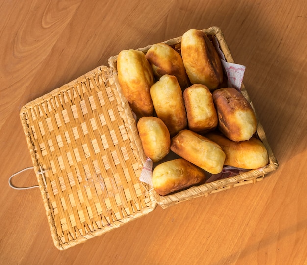 伝統的な自家製焼きたてのパテまたはジャムとパイの枝編み細工品バスケット。イースト生地から素朴なスタイルで作られたロシアの揚げピロシキ