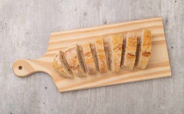 Foto fette di pane baguette francesi fatte in casa tradizionali su tavola di legno.