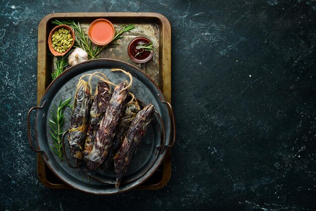 Traditional homemade horse sausage Sausage with spices on a black stone background Top view Free space for text