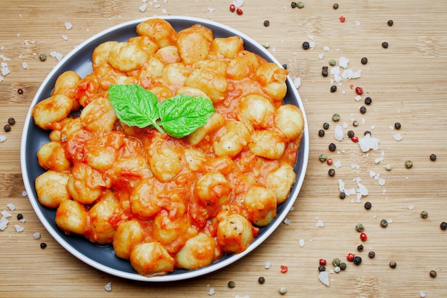 Foto gnocchi italiani tradizionali fatti in casa in salsa aromatica di pomodoro serviti su un piatto decorativo