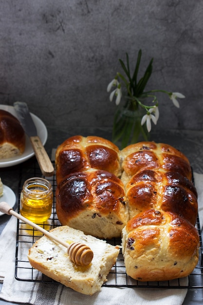 Traditional hot cross buns with honey and butter on a concrete surface