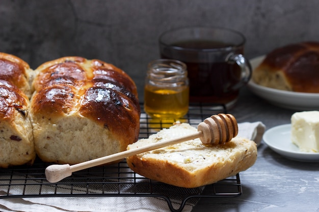 Traditional hot cross buns with honey and butter on a concrete surface