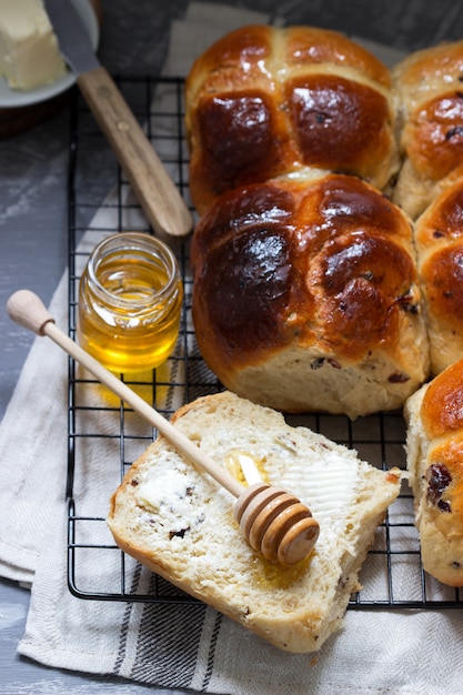 Traditional hot cross buns with honey and butter on a concrete surface