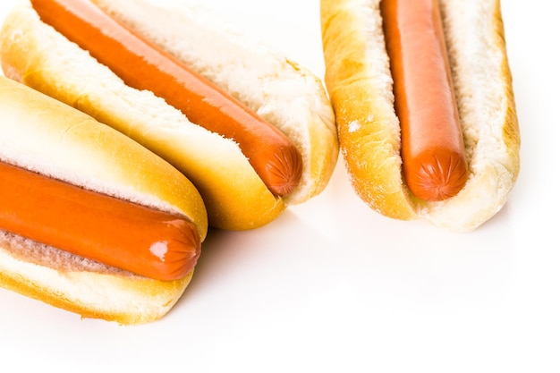 Traditional hot dogs on a white hot dog bun on a white background.