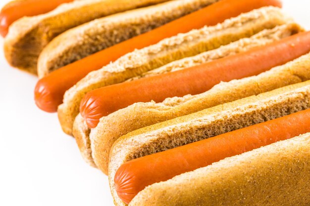 Traditional hot dogs on a white hot dog bun on a white background