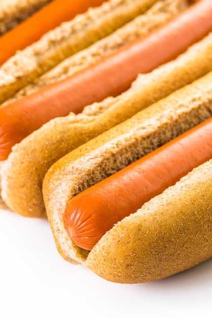 Traditional hot dogs on a white hot dog bun on a white background.