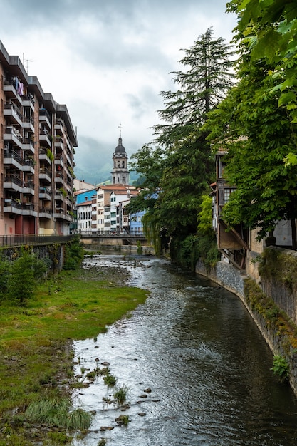 Traditional houses in the town of Azkoitia next to the Urola river and Church of Santa MarÃ­a La Real in the background, Gipuzkoa. Basque Country