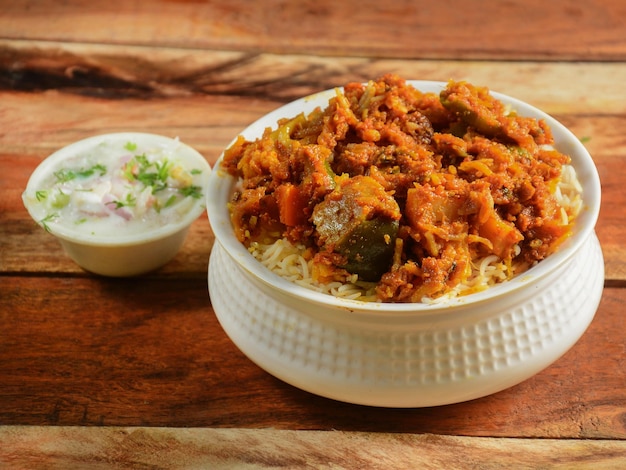 Tradizionale verdura hyderabadi dum biryani con verdure miste servita con fuoco selettivo raita misto