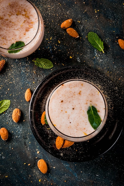 Photo traditional indian beverage, holi festival food, thandai sardai milk drink with nuts, spices, mint. dark blue background, copy space