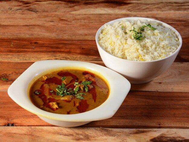 사진 소박한 나무 배경에 흰색 세라믹 그릇에 전통적인 인도 요리 쇠고기 카레와 삶은 쌀