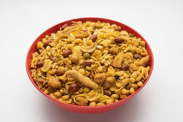 Traditional indian deep fried salty dish - chivda or mixture or farsan or farsaan made of gram flour and mixed with dry fruits served in a bowl or plate