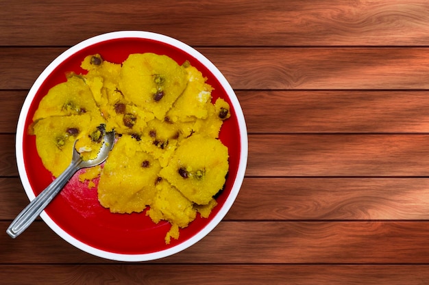 Traditional Indian dessert kesari with raisins on red plate on wooden table top view