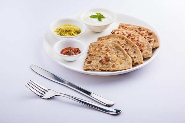 전통적인 인도 음식 Aloo paratha 또는 감자 박제 납작한 빵. 다채로운 또는 나무 배경 위에 토마토 케첩과 커드와 함께 제공됩니다. 선택적 초점