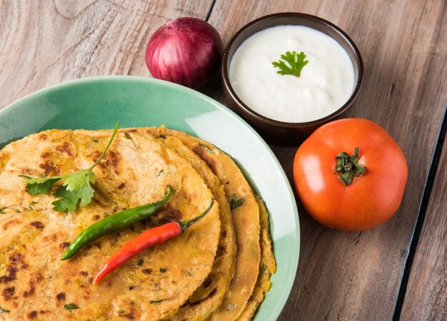 전통적인 인도 음식 Aloo paratha 또는 감자 박제 납작한 빵. 다채로운 또는 나무 배경 위에 토마토 케첩과 커드와 함께 제공됩니다. 선택적 초점