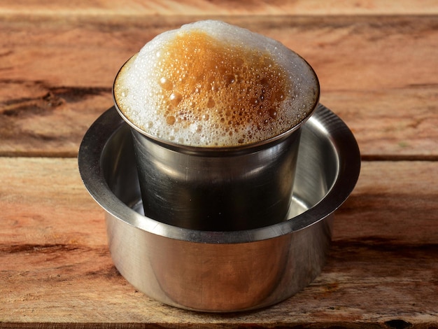 Traditional Indian Madras filter coffee in a steel cup also known as tumbler and dabarah south indian style selective focus