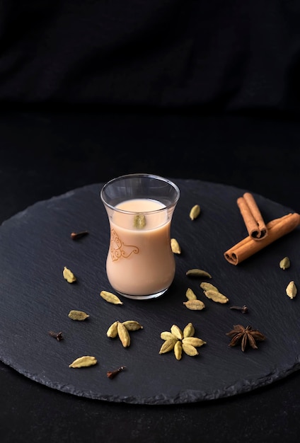 Traditional indian and middle eastern hot drink masala tea or karak chai with spice and milk. Exotic cuisine. Black background.