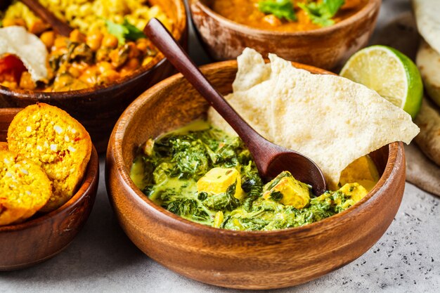 Traditional Indian palak paneer in wooden bowl on white table.