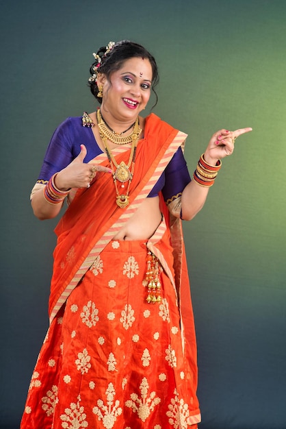 伝統的なインド人女性が幸せな顔で手や指で何かを指差し,プレゼントしています