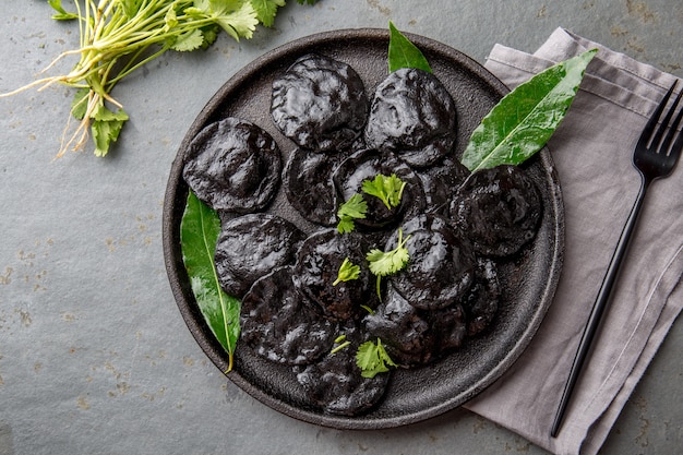 Traditional Italian black ravioli on black plate