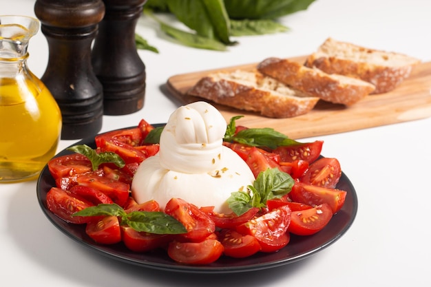 맛있는 체리 토마토, 바질 잎, 올리브 오일 샐러드를 곁들인 이탈리아 전통 부라타 치즈