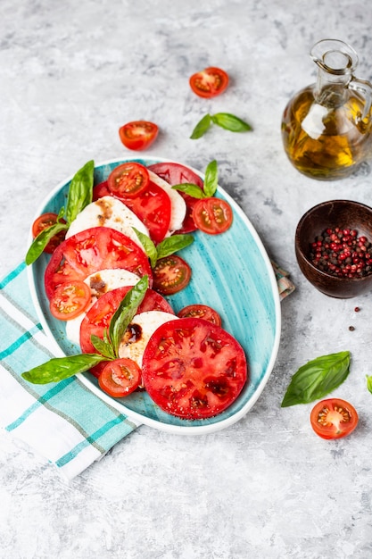 Traditional Italian caprese salad with sliced tomatoes, mozzarella cheese, basil, olive oil