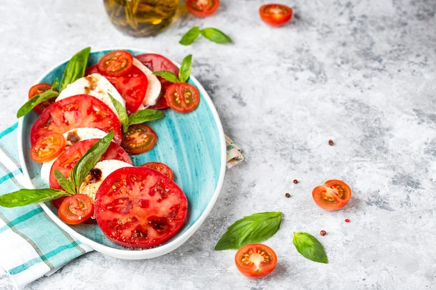 Traditional Italian caprese salad with sliced tomatoes, mozzarella cheese, basil, olive oil