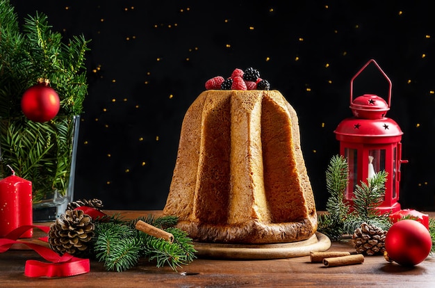 Traditional Italian Christmas cake Pandoro on wooden table with decoration lights on dark background