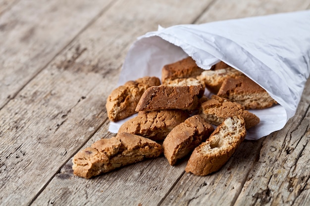 Traditional Italian cookies cantuccini on white paper bag on ructic wooden table