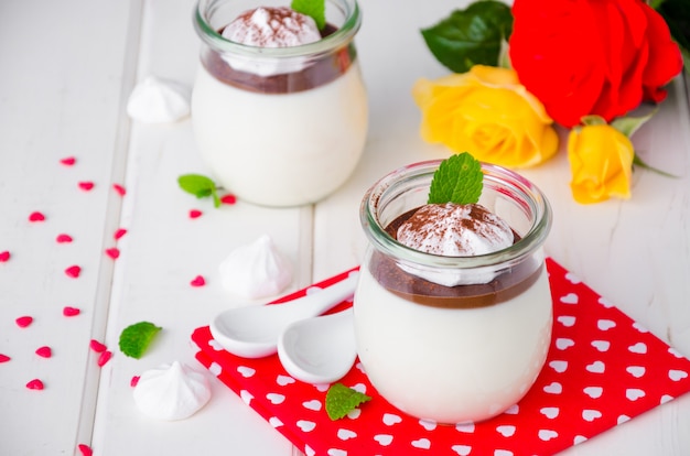 Traditional Italian dessert panna cotta with chocolate sauce and crispy meringue, dessert for Valentine's Day served in glass jars.