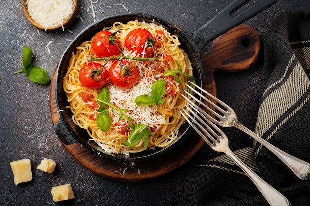 Traditional Italian dish of spaghetti with tomato sauce and parmesan cheese in iron frying pan