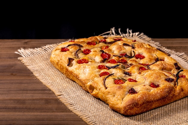 Photo traditional italian focaccia with cherry tomatoes, black olives and rosemary.