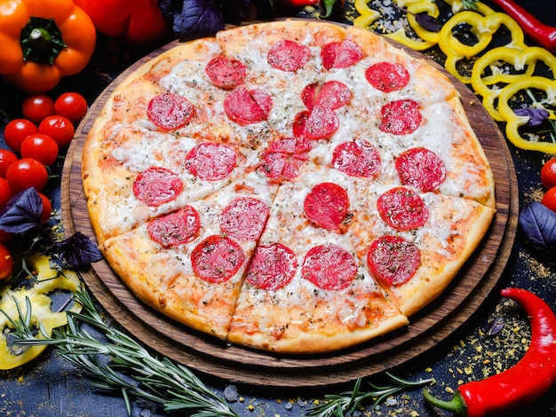 Traditional italian food. pizza pepperoni with melted cheese, fresh vegetables in background