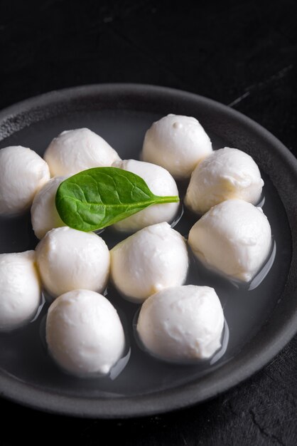 Traditional Italian Mozzarella cheese and basil on rough ceramic plate and black surface