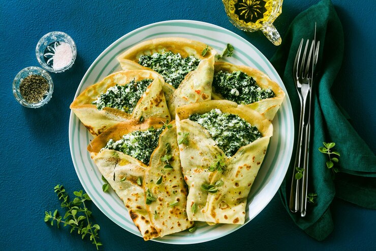 Traditional Italian pancakes crepes with spinach and ricotta on a served blue table healthy vegetarian diet