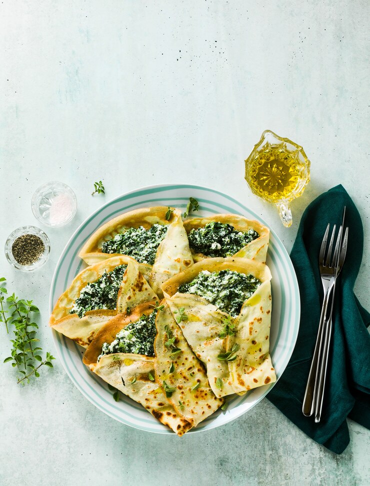 Traditional Italian pancakes crepes with spinach and ricotta on a served table. healthy vegetarian diet