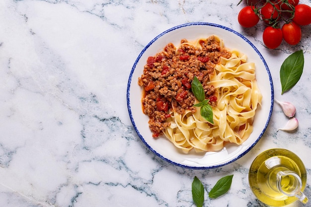 Traditional italian pasta bolognese on a white plate on a marble background