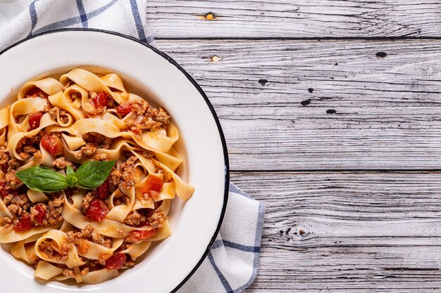 Foto pasta tradizionale italiana alla bolognese su un piatto bianco su sfondo di legno