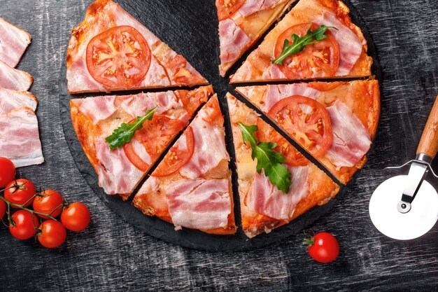 Traditional italian pizza with mozzarella cheese, ham, tomatoes, pepper, pepperoni spices and fresh rucola