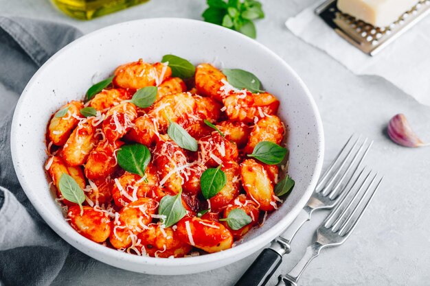 Traditional Italian potato Gnocchi with tomato sauce parmesan cheese and fresh basil in the bowl