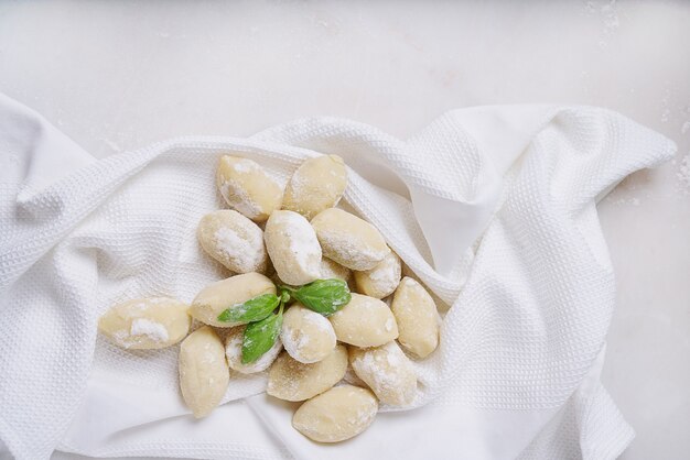 Traditional italian potato gnocci  (pasta) decorated with basil leaf. Uncooked pasta concept. Top View. Flat Lay