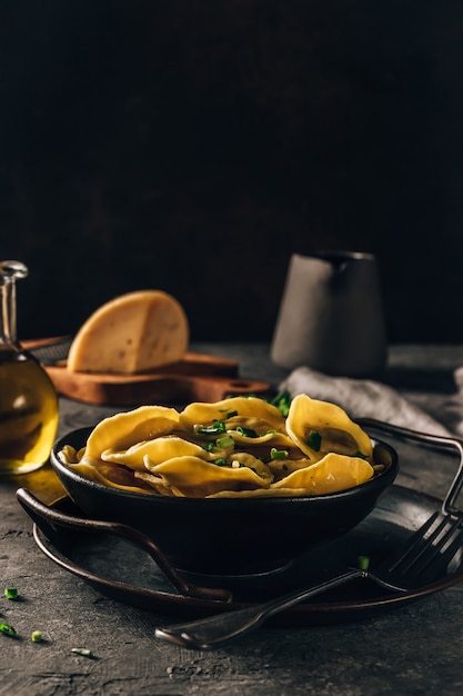黒い皿の暗い背景のセレクティブ フォーカスにチーズを詰めた伝統的なイタリアのラビオリ