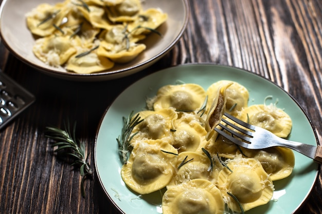 Traditional italian ravioli with rosemary and parmesan served on a rustic wooden table. Italian pasta