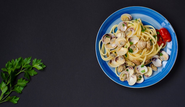 Concetto di pesce italiano tradizionale. spaghetti con vongole veraci o shelfish, pomodoro ed erbe