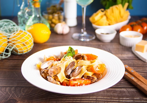 Традиционная итальянская паста из морепродуктов на белой тарелке с моллюсками вонголе с помидорами и базиликом Вкусная и вкусная еда
